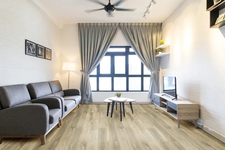 Modern living room with gray sofa, TV, and large window with curtains.