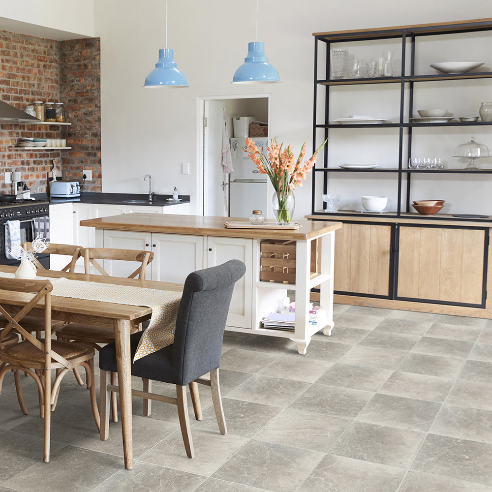 Modern kitchen with wooden dining table and chairs, gray tiles on the floor, and a brick wall.
