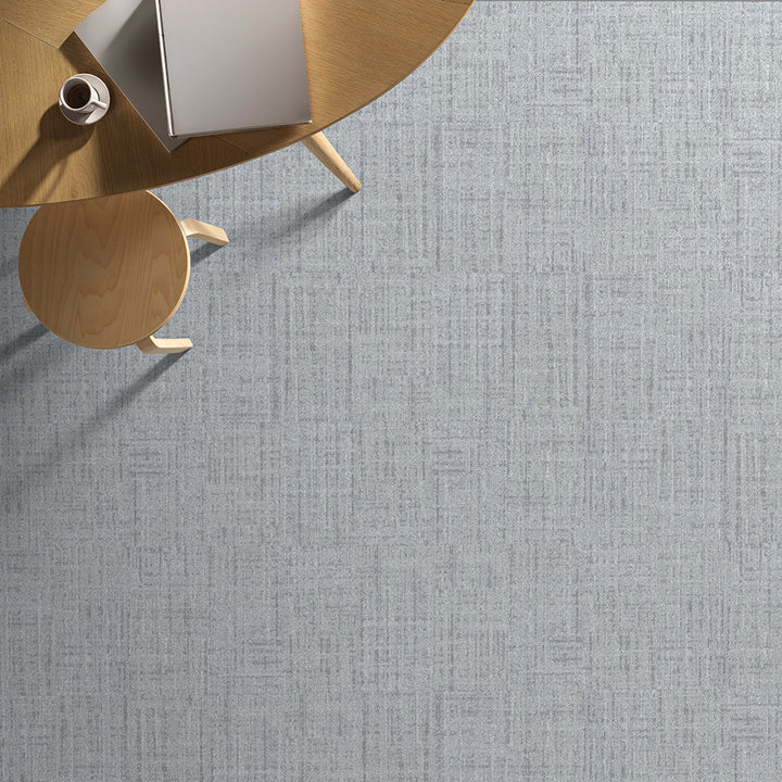 Gray textured carpet with a wooden coffee table and chair in the corner.