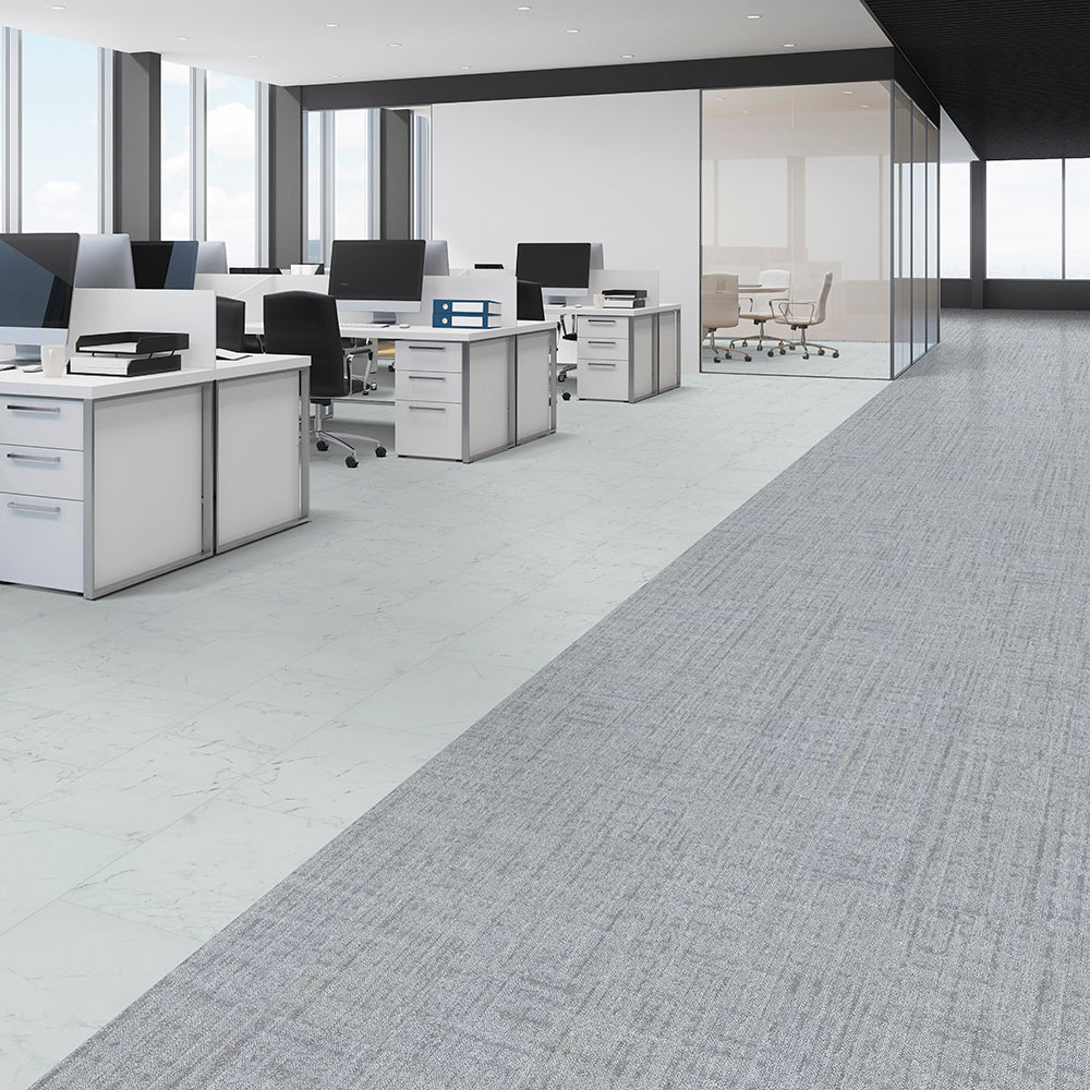 Modern office with gray carpeted floor and white desks.