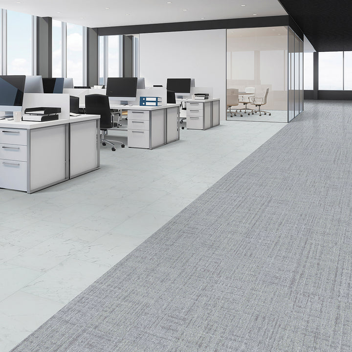 Modern office with gray carpeted floor and white desks.