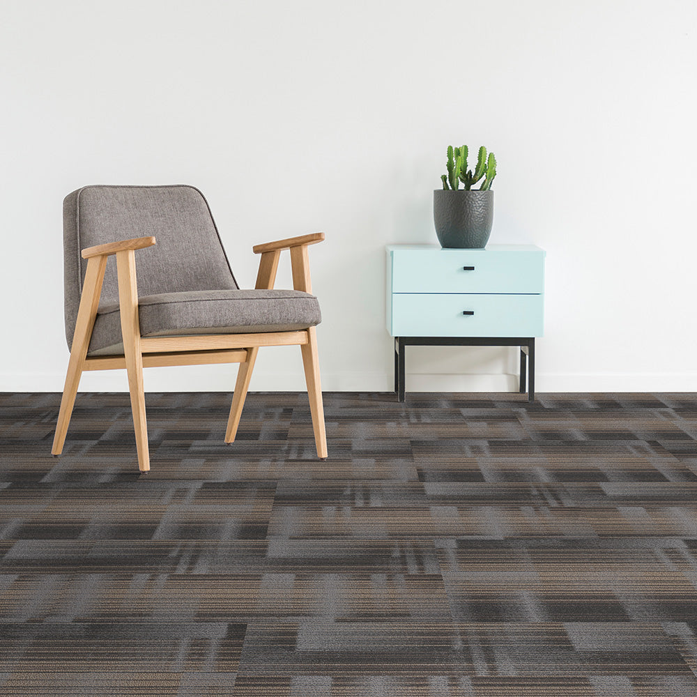 Gray chair and light blue cabinet with a potted plant on a patterned carpet.