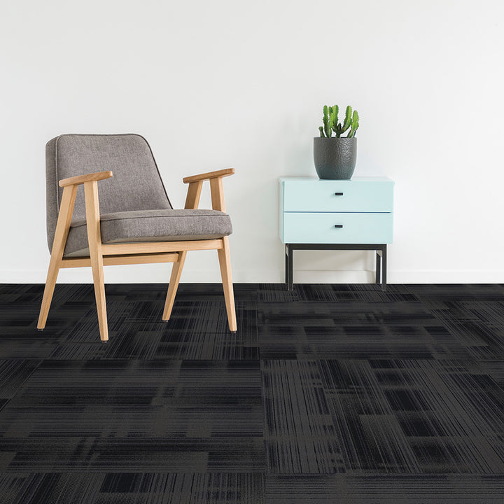 Gray chair and light blue cabinet with a potted plant on a black patterned carpet.