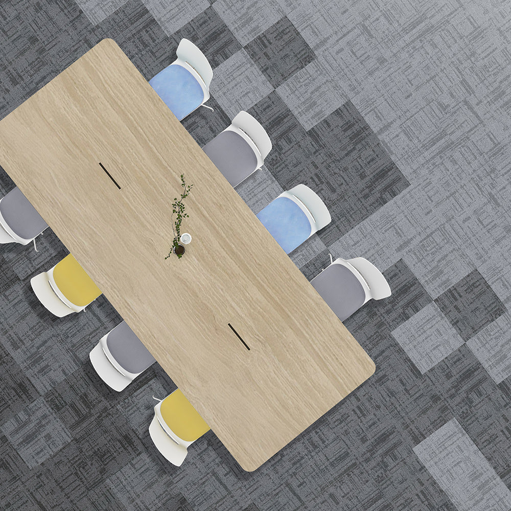 Top-down view of a long wooden table with chairs on a gray patterned floor.