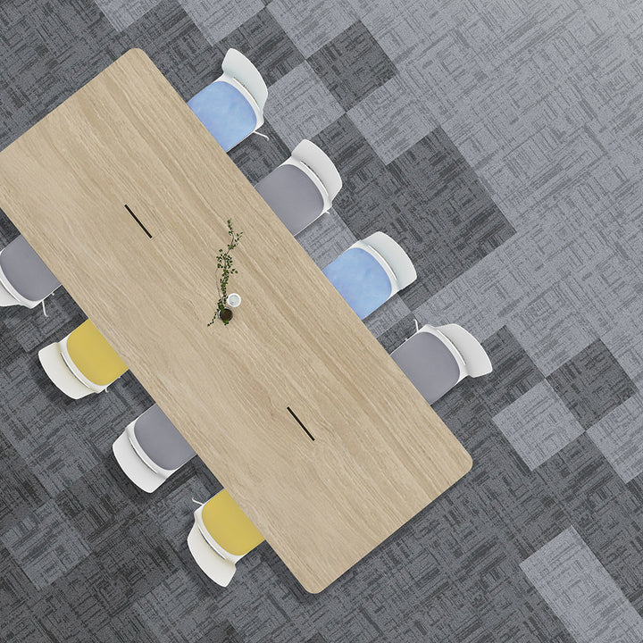 Top-down view of a long wooden table with chairs on a gray patterned floor.