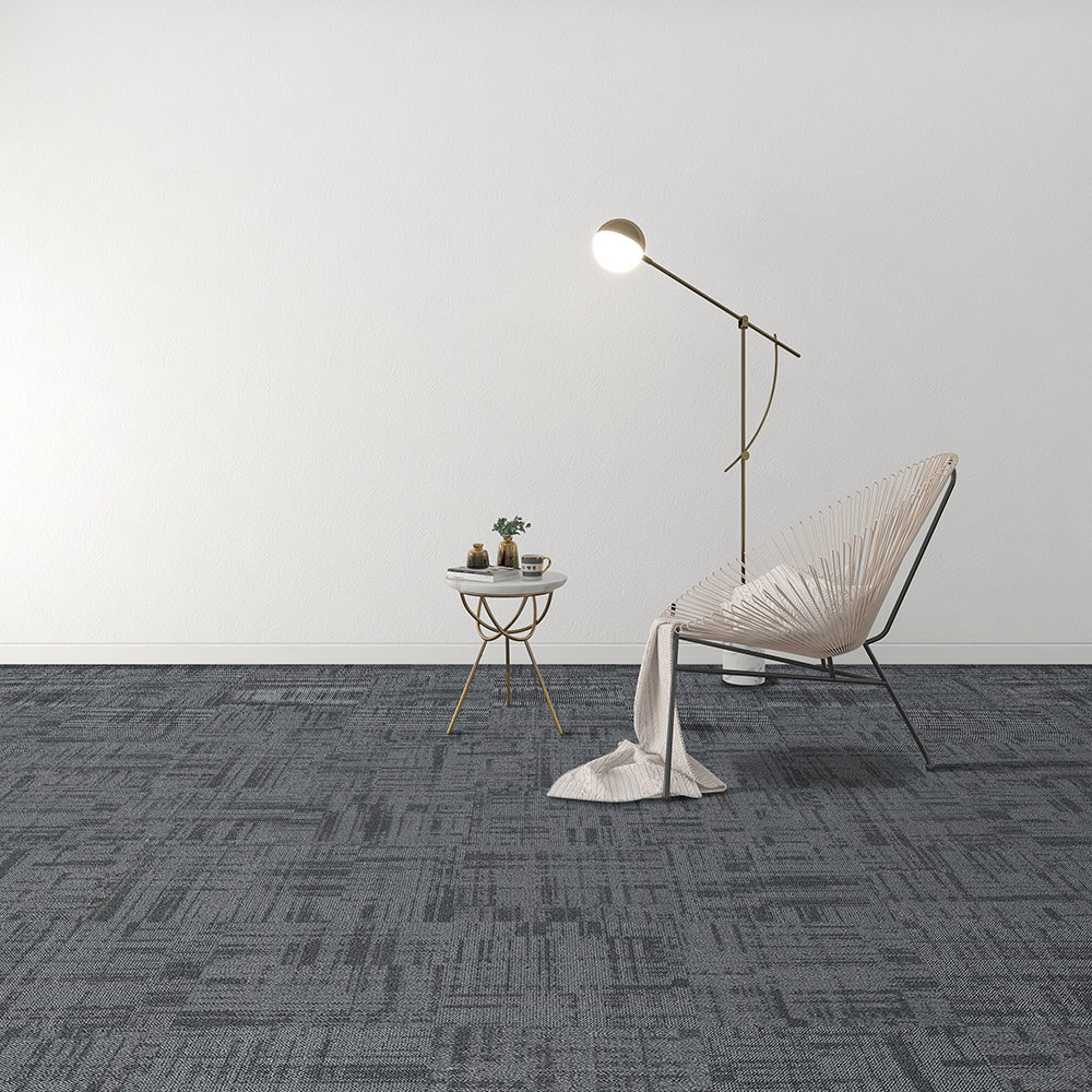 Modern room with a chair, side table, and floor lamp on a gray patterned carpet.