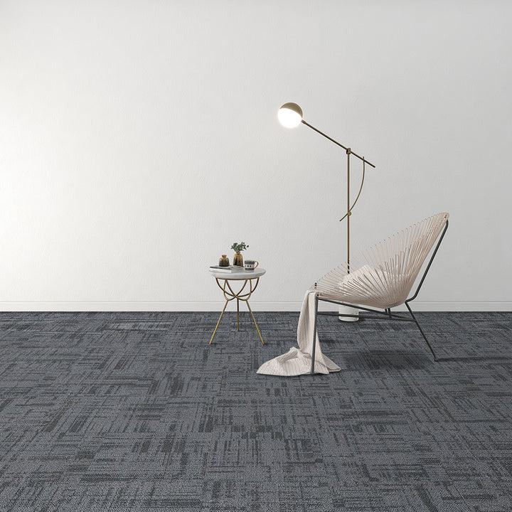 Modern room with a chair, side table, and floor lamp on a gray patterned carpet.