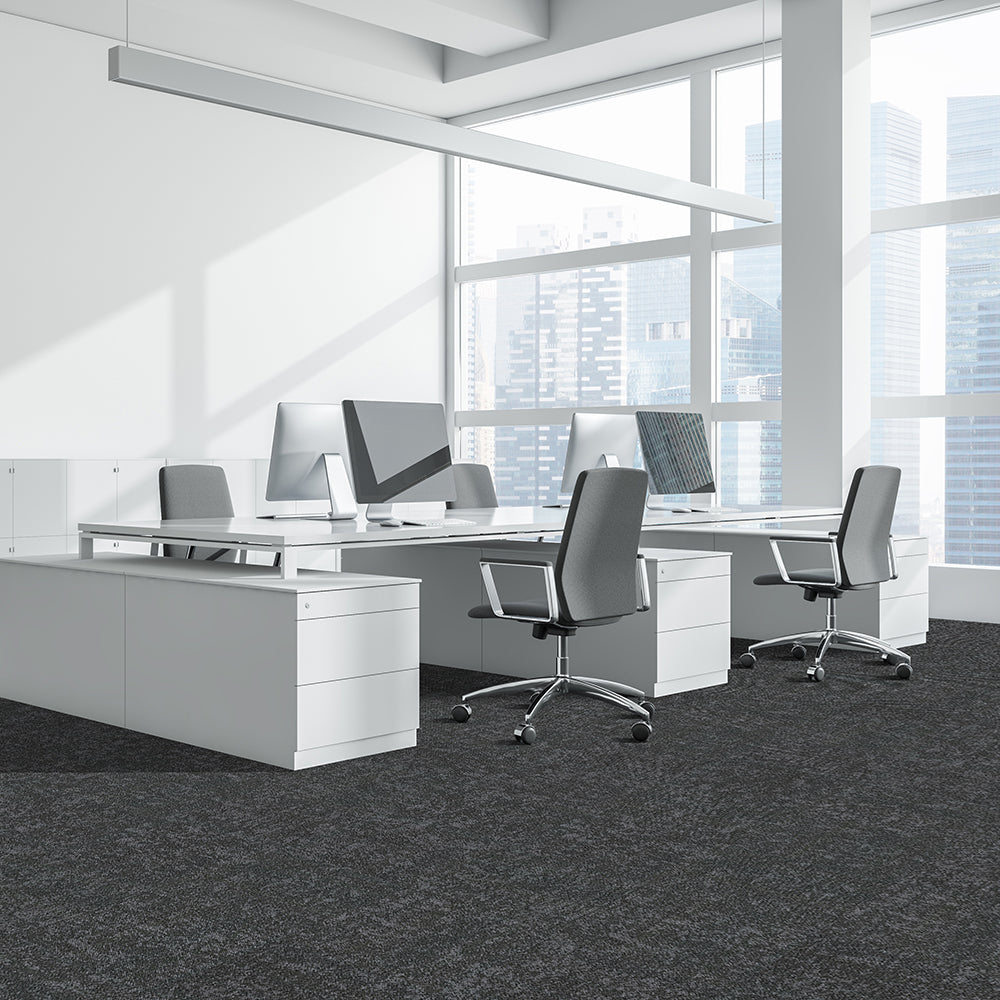 Modern office setup with white desks, chairs, and computer monitors in a bright room.