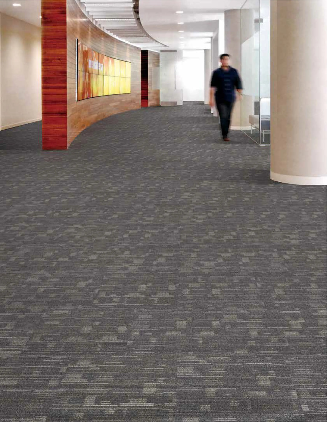 Person walking down a carpeted hallway in an office building