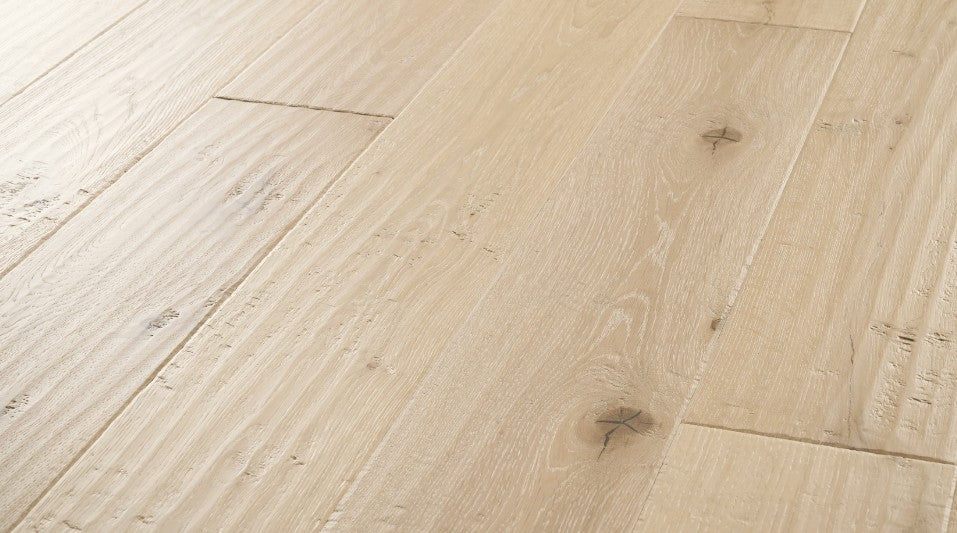 Close-up of Carrara engineered hardwood flooring from the Atelier Collection featuring hand-scraped white oak with blonde natural tones and 3 mm veneer.
