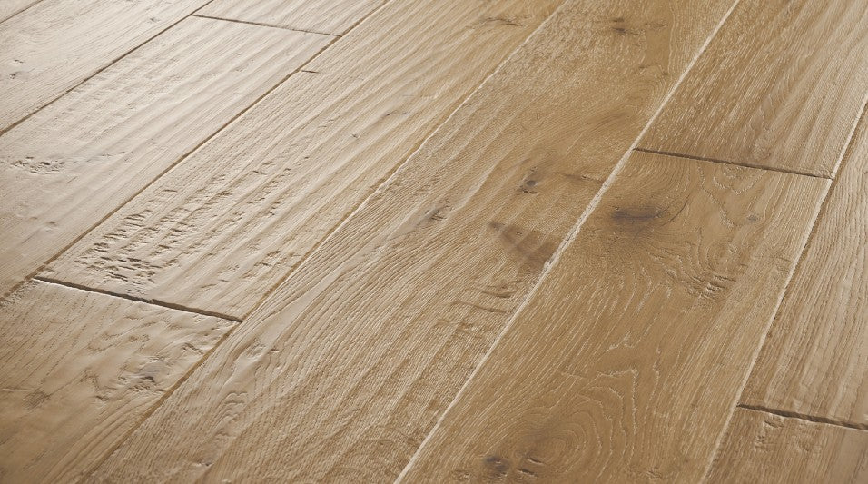 Close-up of Clayborn engineered hardwood flooring from the Atelier Collection featuring hand-scraped white oak with natural brown tones and 3 mm veneer.