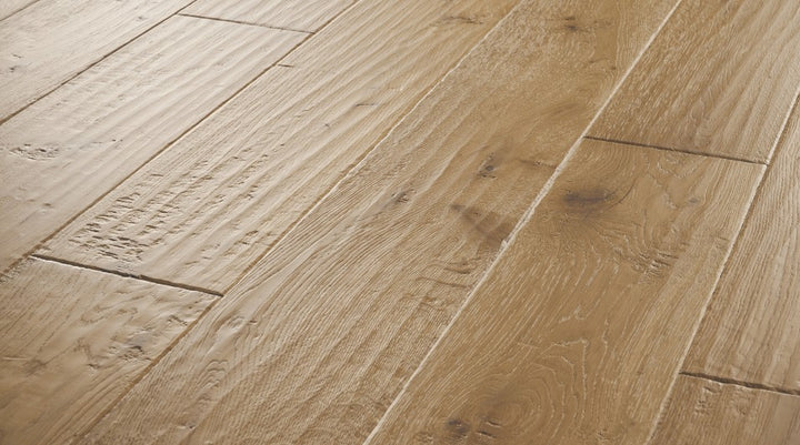 Close-up of Clayborn engineered hardwood flooring from the Atelier Collection featuring hand-scraped white oak with natural brown tones and 3 mm veneer.