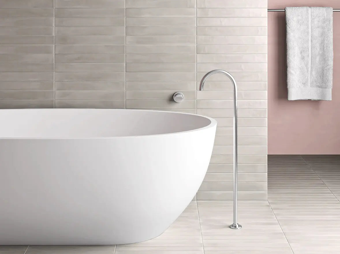 Modern freestanding bathtub in a bathroom with tiled walls and a towel.