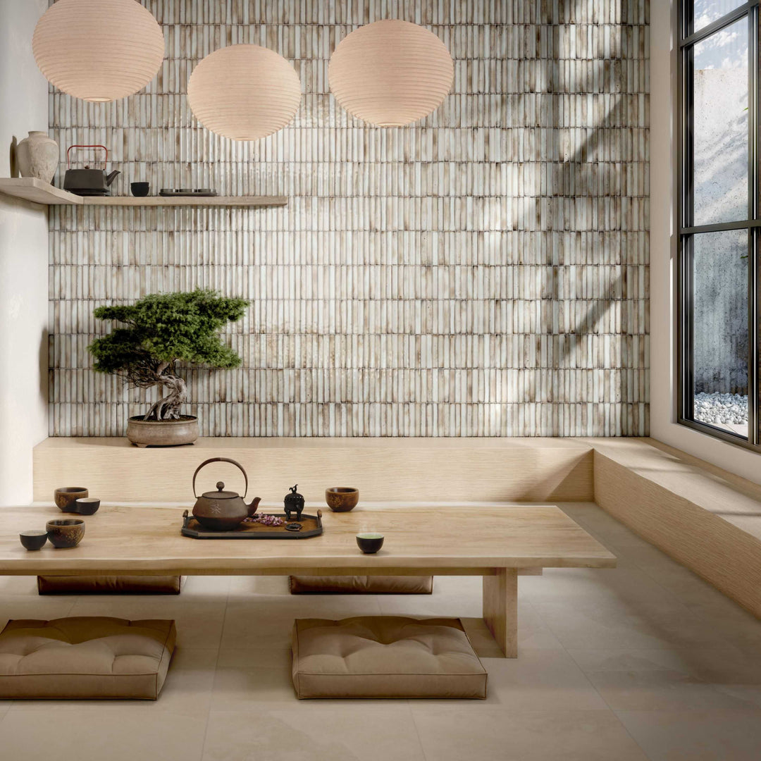 Modern interior with a wooden table, teapot, and bonsai tree against a bamboo wall.