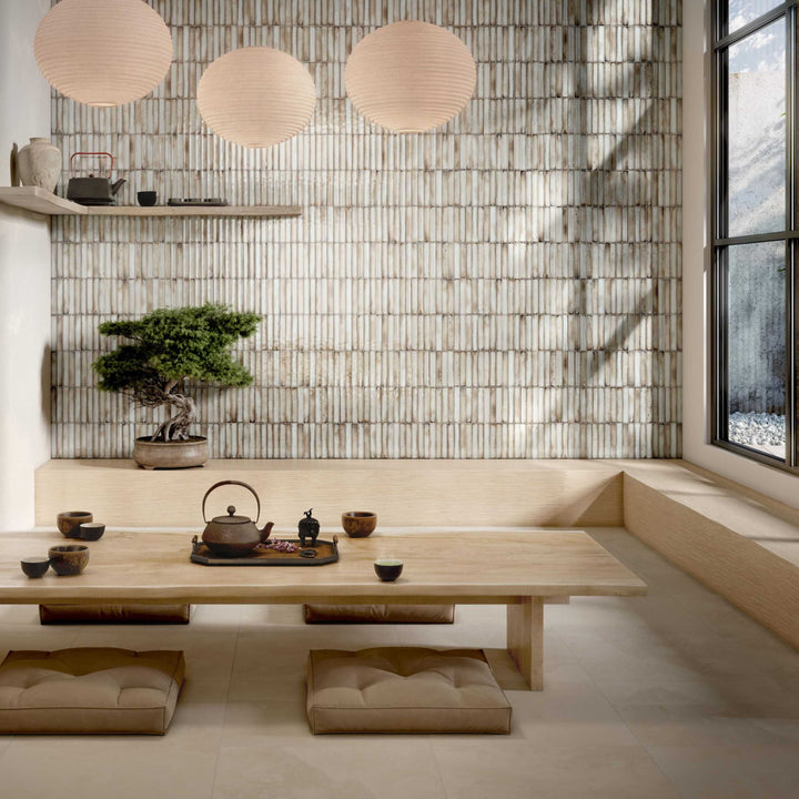 Modern interior with a wooden table, teapot, and bonsai tree against a bamboo wall.
