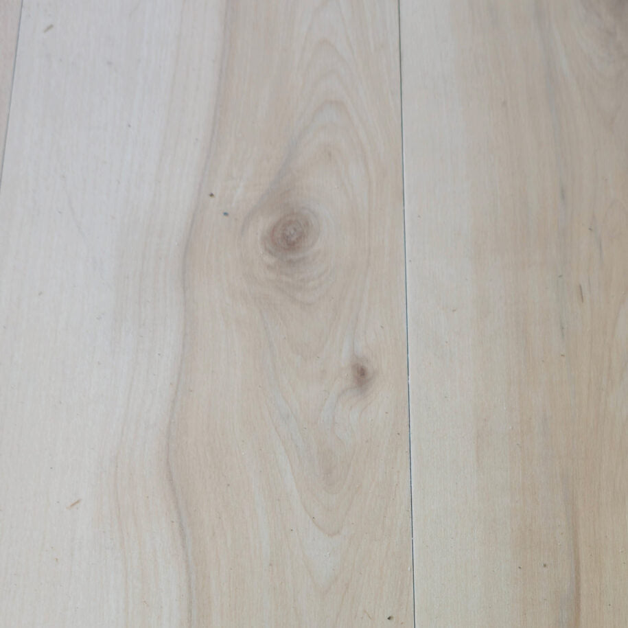 Close-up of light vinyl flooring in natural maple color with visible grain and texture