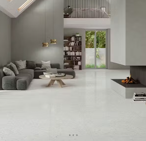 A modern living room with large format white porcelain tiles resembling natural slate, with a gray sofa, low coffee table, and a fireplace.