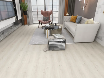 A living room scene with a stylish arrangement of furniture, featuring a beige laminate floor with a wood grain finish. A modern fireplace, a white sofa, a checkered ottoman, and a flat-screen TV are visible in the background.