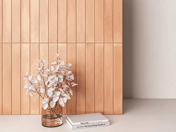 Vase with white flowers on a surface against a wooden panel wall.